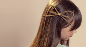A girl with straight brown hair wearing a bow-shaped hair clip